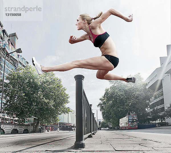 Sportler springt über Geländer auf Straße