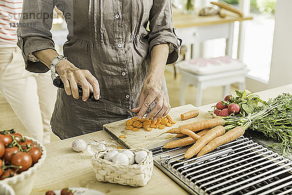 Ausgeschnittene Aufnahme einer älteren Frau  die in der Küche frisches Gemüse zubereitet