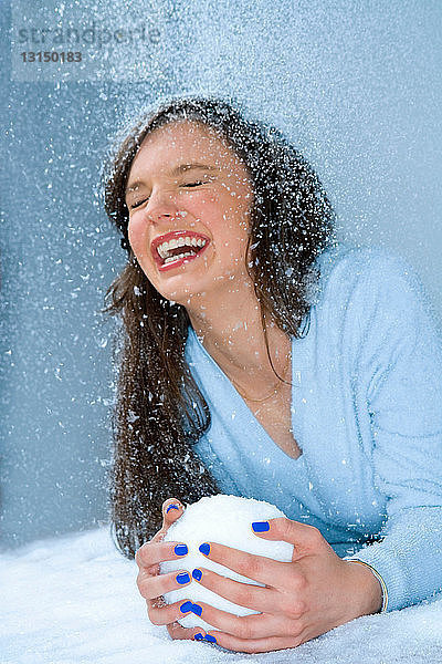 Frau lacht im Schnee  hält Schneeball