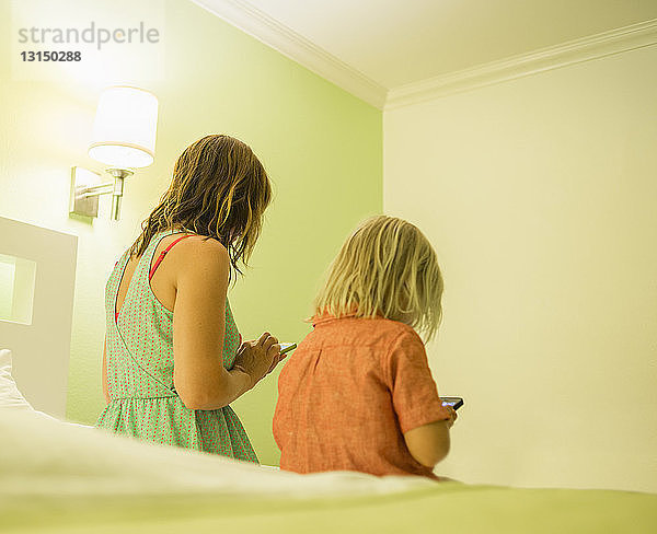 Mutter und Sohn benutzen Smartphone auf dem Bett