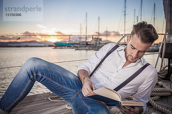 Junger Mann liest auf einer Yacht  Cagliari  Sardinien  Italien