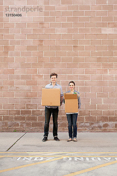 Porträt eines jungen Paares  das Kartonschachteln in einer Laderampe hält
