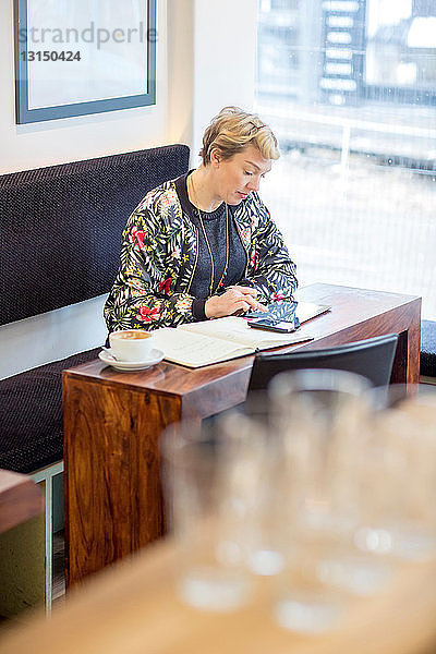 Frau benutzt digitales Tablet in einem Cafe