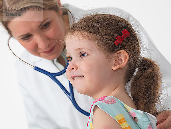 Kinderarzt beim Abhören von Herz und Lunge eines kleinen Mädchens im OP