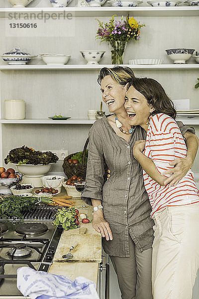 Ältere Frau  die ihre Tochter in der Küche umarmt