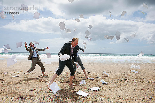 Geschäftsleute  die am Strand Papiere wegwerfen