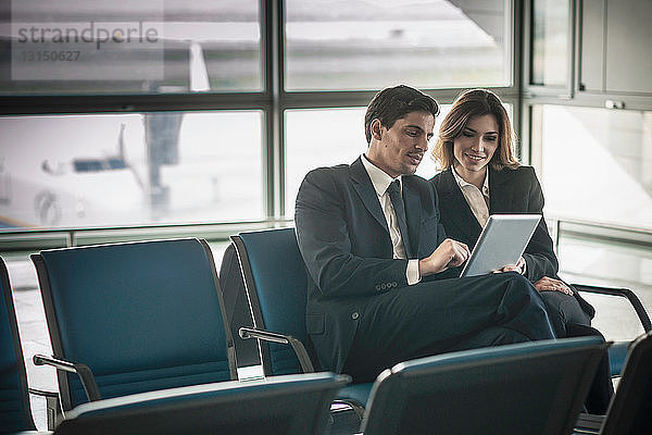 Geschäftsleute nutzen digitale Tabletten in der Abflughalle eines Flughafens