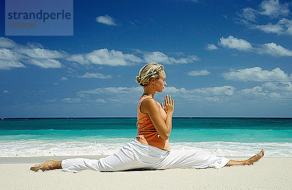 Frau übt Yoga am tropischen Strand