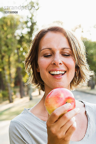 Lächelnde Frau isst Apfel im Freien