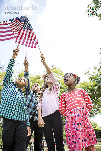 Kinder halten amerikanische Flaggen im Park hoch