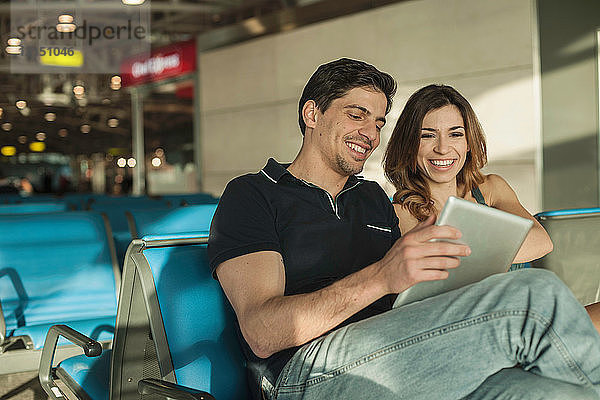 Junges Paar benutzt digitales Tablet in der Abflughalle eines Flughafens