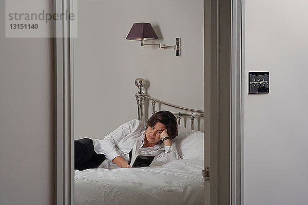 Reife Frau liest Buch auf dem Bett