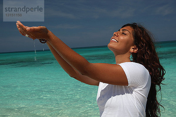 Junge Frau am Strand mit Händen  die Wasser schröpfen  Paradise Island  Nassau  Bahamas