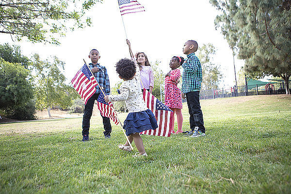 Kinder halten amerikanische Flaggen im Park hoch