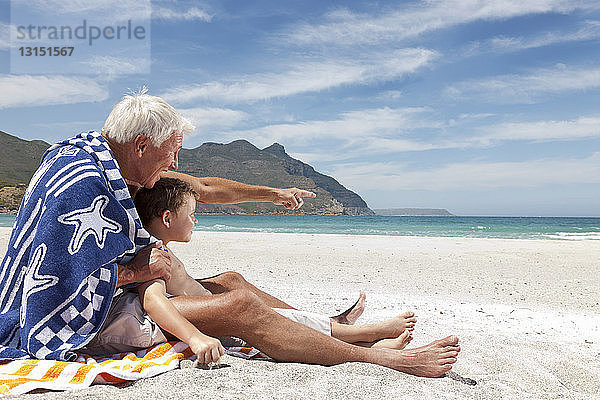 Älterer Mann mit Enkel am Strand