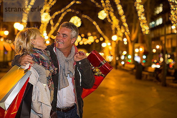 Älteres Paar mit Weihnachtseinkäufen auf einer von Bäumen gesäumten Allee  Mallorca  Spanien