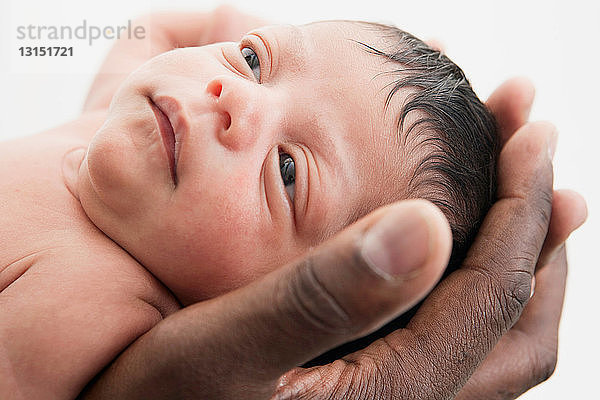 Vater hält den Kopf eines kleinen Babys