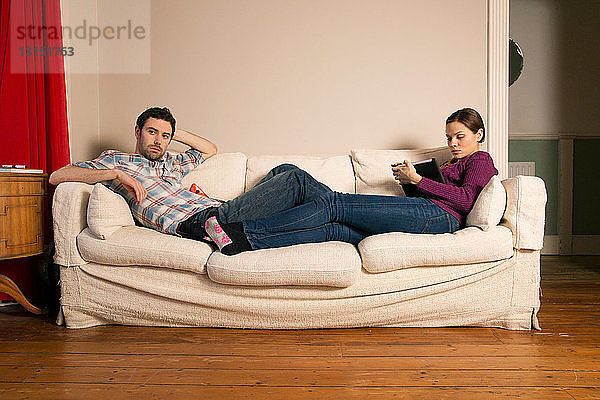 Junges Paar sitzt auf Sofa
