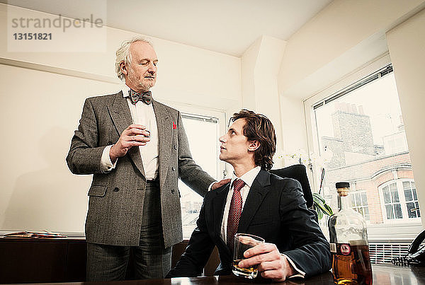 Zwei Männer trinken Spirituosen im Büro
