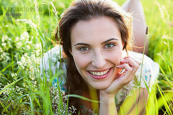 Lächelnde Frau im hohen Gras liegend