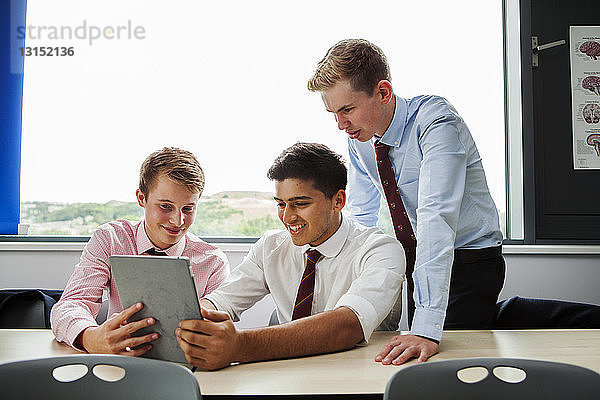 Teenager-Schüler sitzen am Schreibtisch mit digitalem Tablet