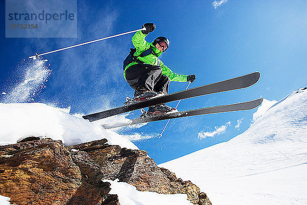 Männlicher Skifahrer springt mit hoher Geschwindigkeit den Berg hinunter