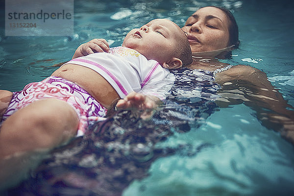 Mutter und kleine Tochter schwimmen auf dem Rücken im Wasser