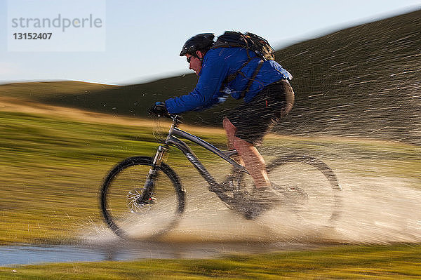 Mountainbiker fährt durch Wasser.