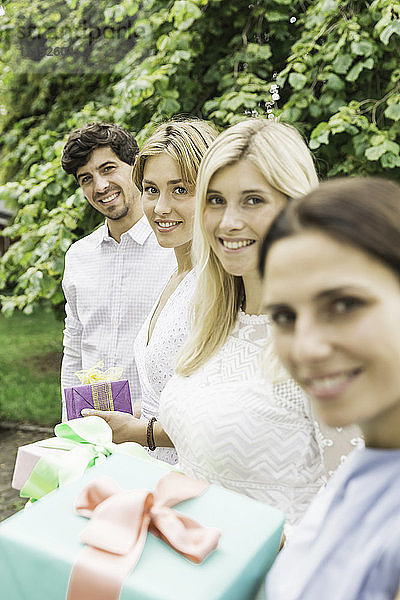 Porträt eines jungen Mannes und dreier Frauen mit Geburtstagsgeschenken im Garten
