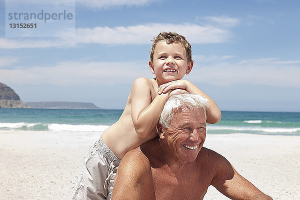 Älterer Mann mit Enkel am Strand