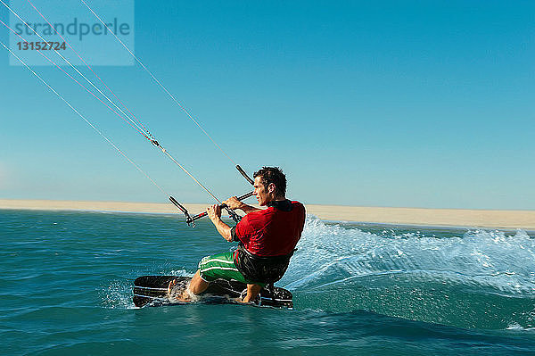 Mann beim Kitesurfen am Strand