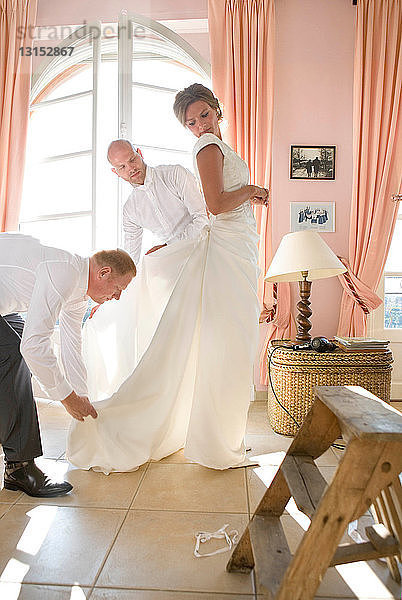Männer helfen der Braut beim Ankleiden