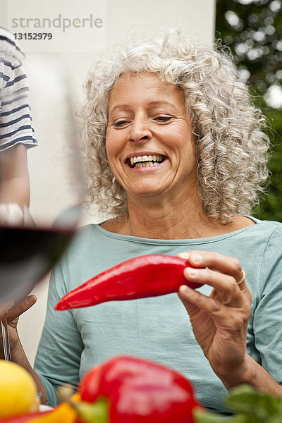 Reife Frau hält eine rote Paprika