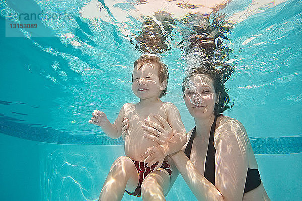 Mutter und Kind lächelnd unter Wasser