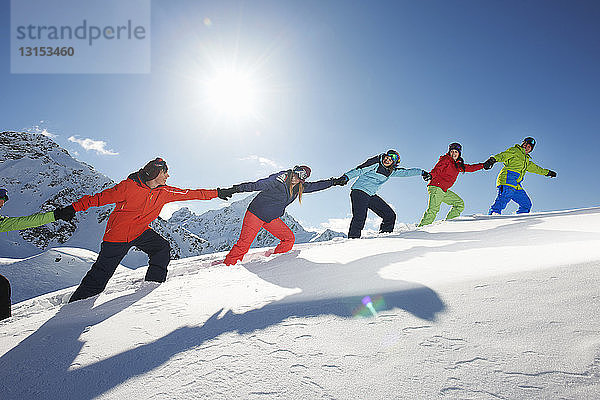 Freunde  die sich gegenseitig im Schnee bergauf ziehen  Kuhtai  Österreich