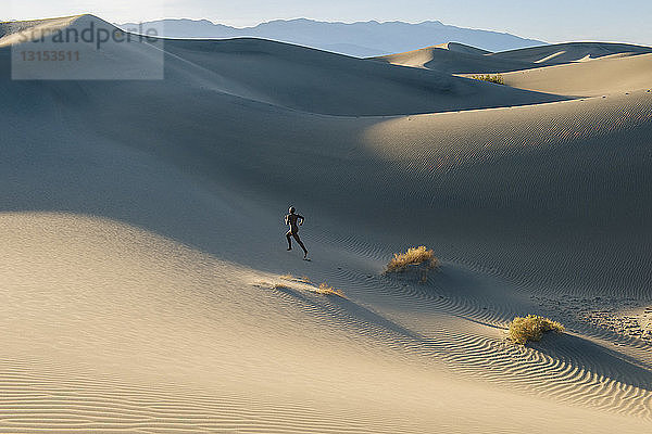 Nackte Frau in der Wüste läuft die Düne hinauf