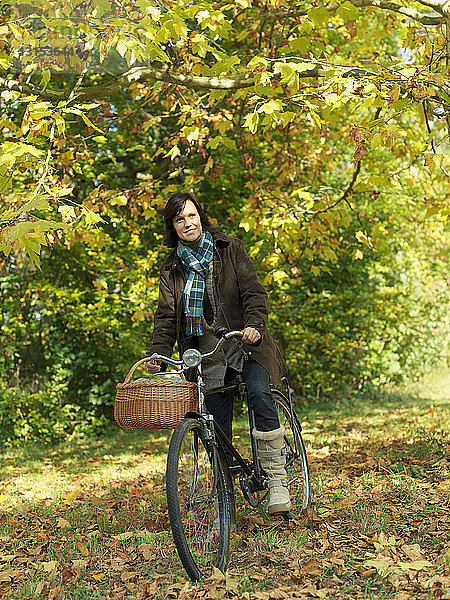 Frau fährt Fahrrad unter Herbstbäumen
