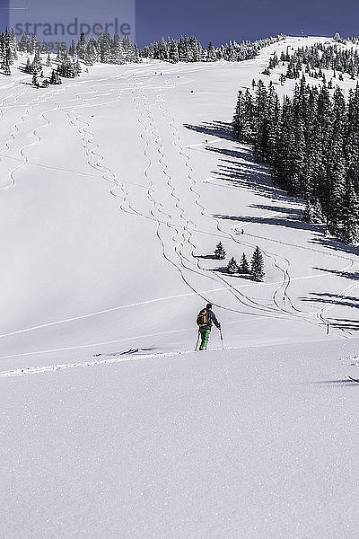 Männlicher Skifahrer beim Aufstieg auf einen schneebedeckten Berg  Spitzingsee  Deutschland