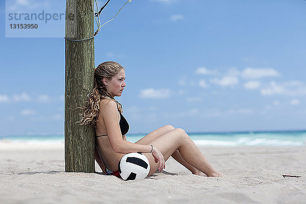 Junge Frau am Strand mit Volleyball