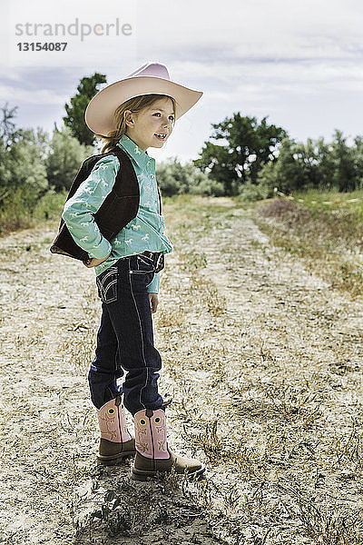 Mädchen mit Cowboyhut und Stiefeln auf einem Weg