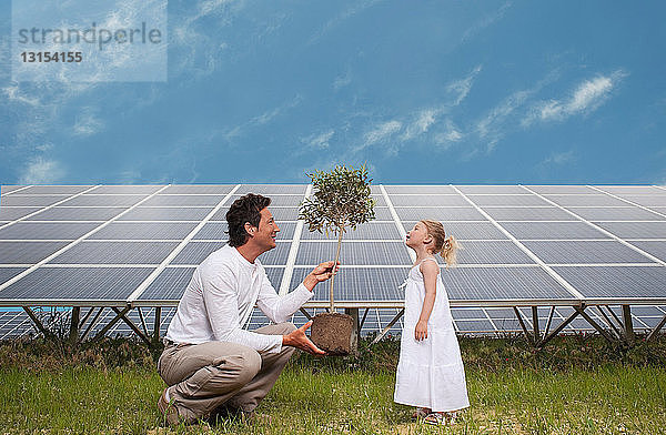 Mann und Tochter vor einem Sonnenkollektor