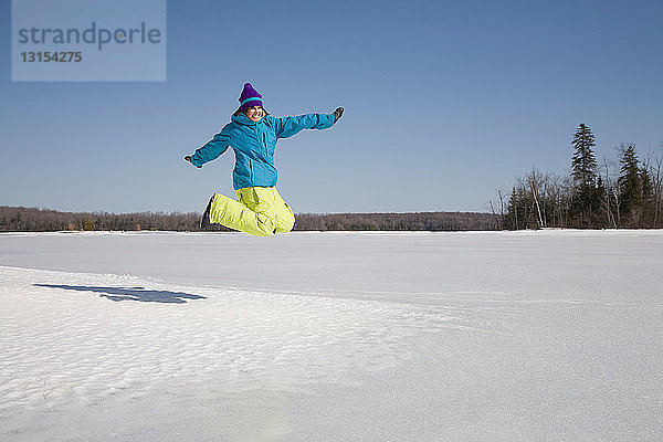 Frau springt auf gefrorenen See