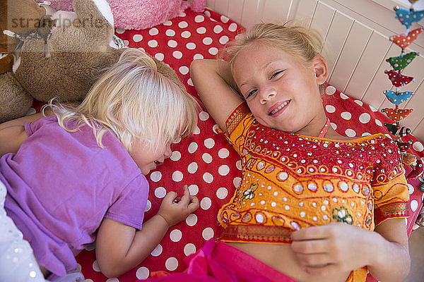 Porträt von zwei jungen Schwestern auf dem Bett liegend