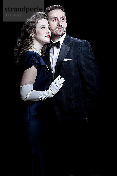 Mid adult couple in 1920's style dress against black background