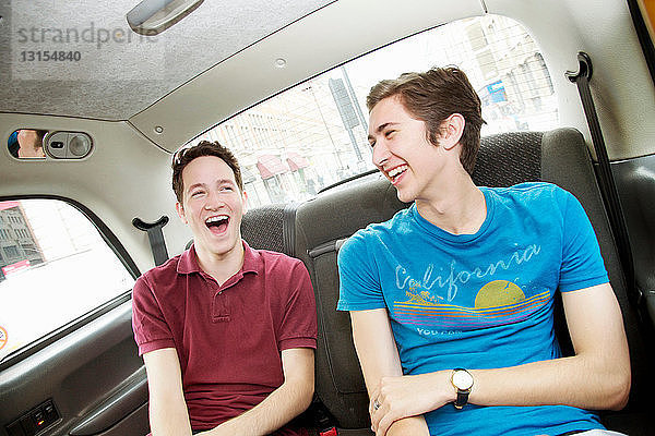 Lachende Männer auf dem Rücksitz eines Autos