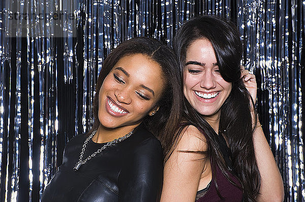 Zwei junge Frauen tanzen Rücken an Rücken in einem Nachtclub