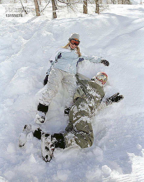 Paar sitzt im Schnee und lacht