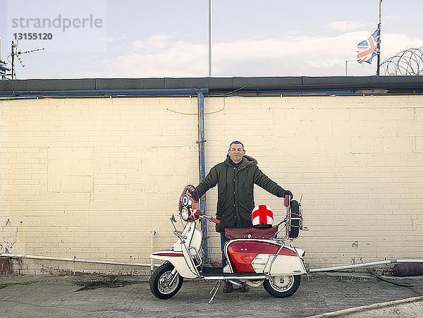 Porträt eines reifen männlichen Mods mit Moped vor einer Wand