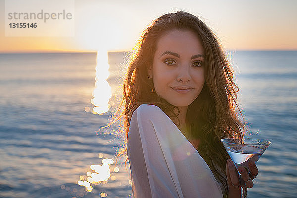 Porträt einer jungen Frau am Strand mit Cocktail bei Sonnenuntergang  Castiadas  Sardinien  Italien