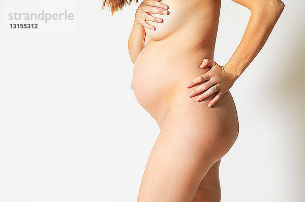 Nackte schwangere Frau bedeckt Brüste